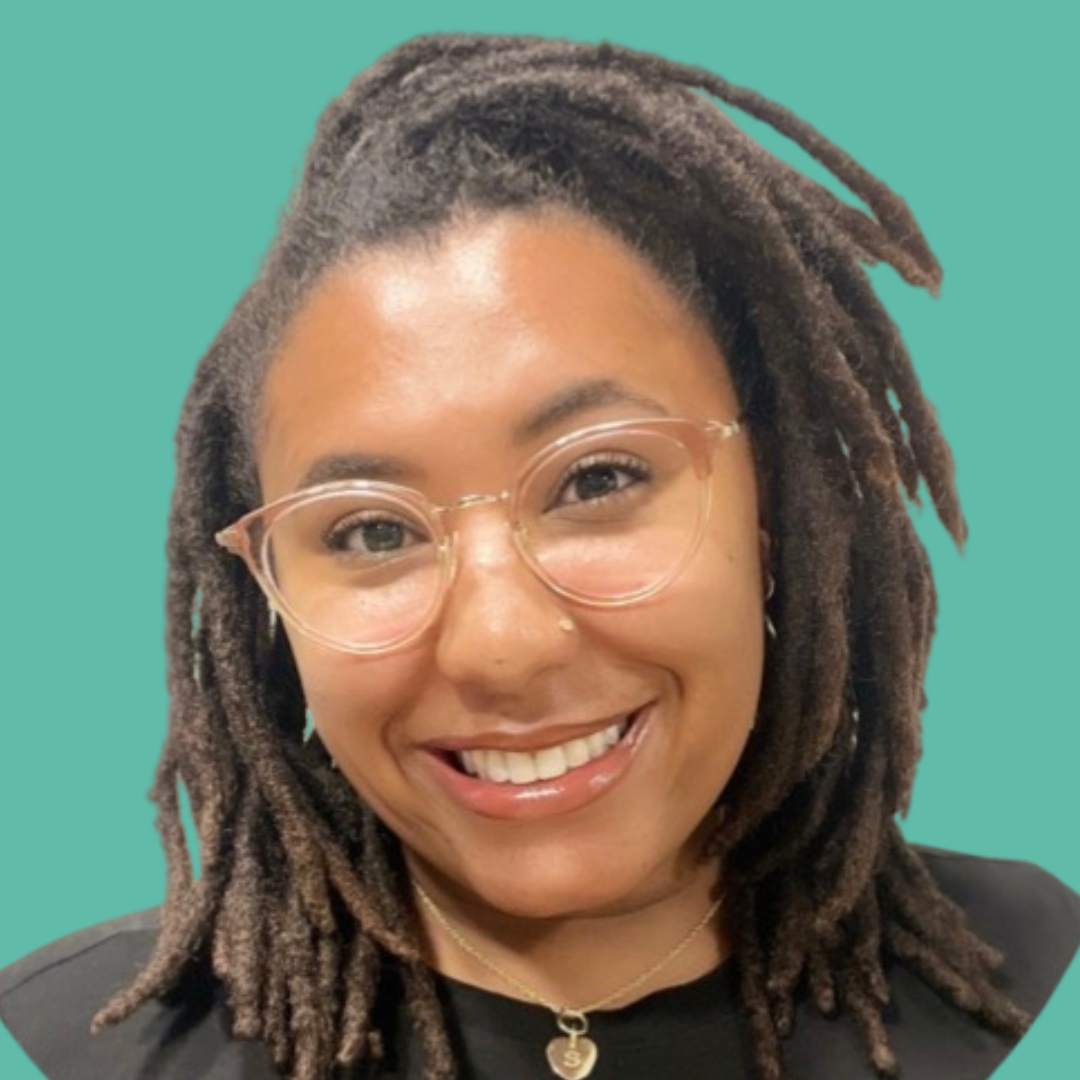 Headshot of Shavon Anderson smiling, with clear glasses and a black shirt, against a solid teal background.